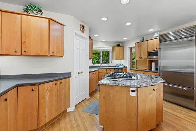 a kitchen with kitchen island granite countertop wooden cabinets and a refrigerator
