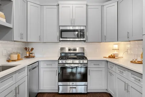 a kitchen with stainless steel appliances granite countertop white cabinets a sink and a stove