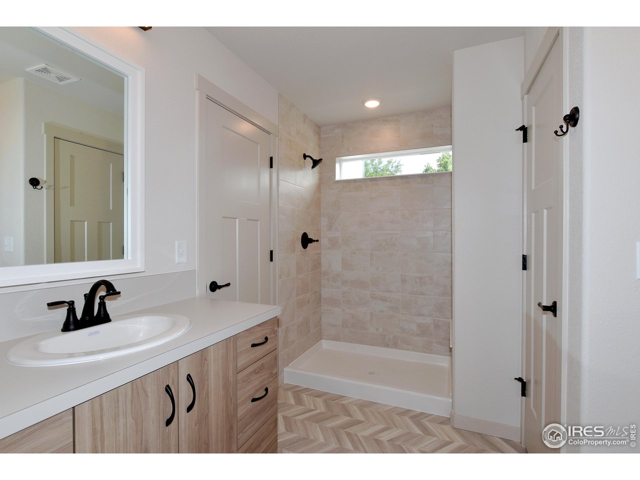 268 East 4th Street Berthoud, CO 80513 - Photo 24 of 39 a bathroom with a sink a mirror a shower and vanity