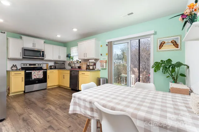 a large white kitchen with a sink dishwasher stove and white cabinets with wooden floor