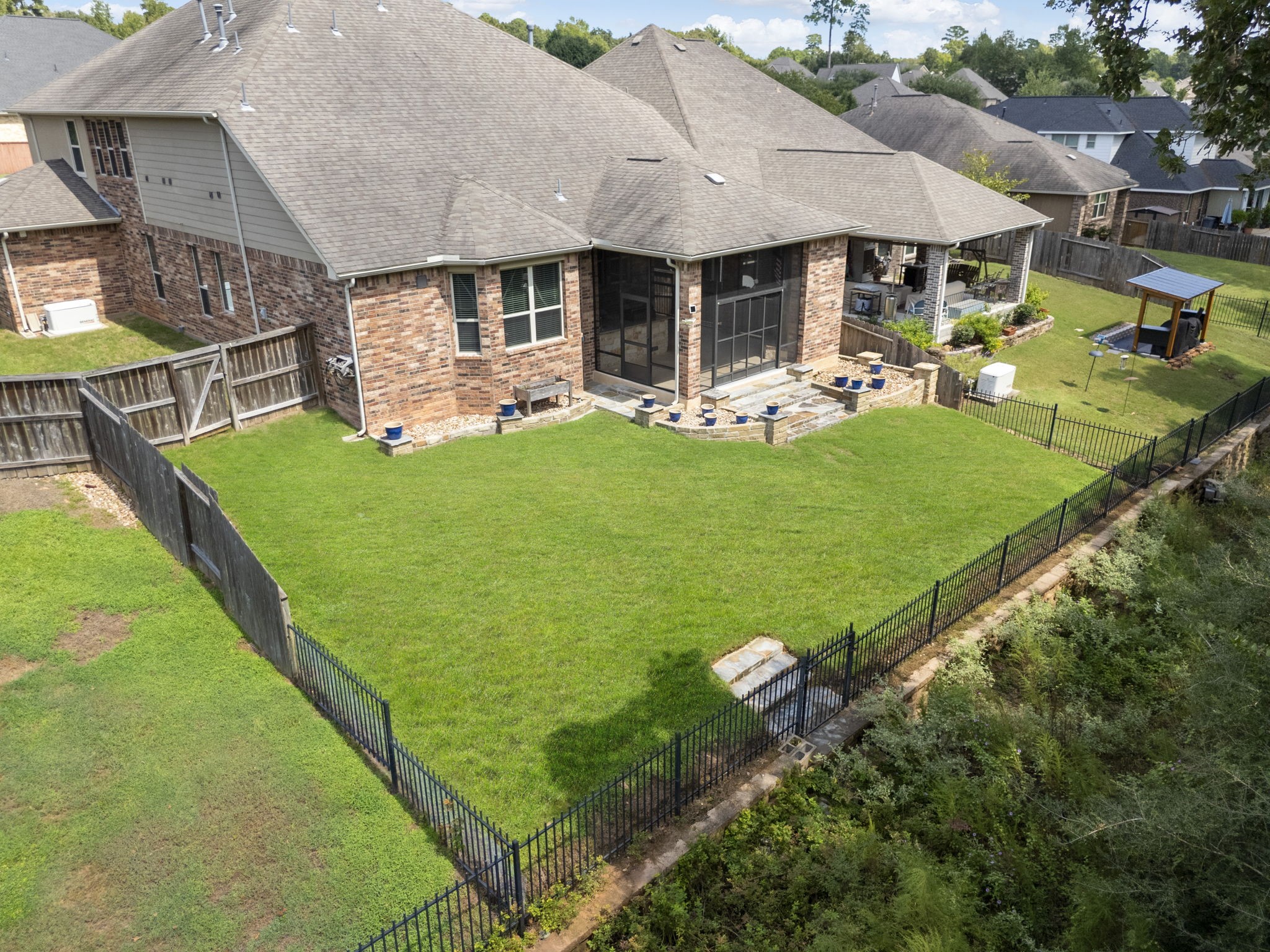 3565 Falcon Way Conroe, TX 77304 - Photo 45 of 50 Aerial rear view showcasing the backyard, screened patio and wooded surroundings.