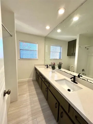 a spacious bathroom with a double vanity sink a mirror and a bathtub