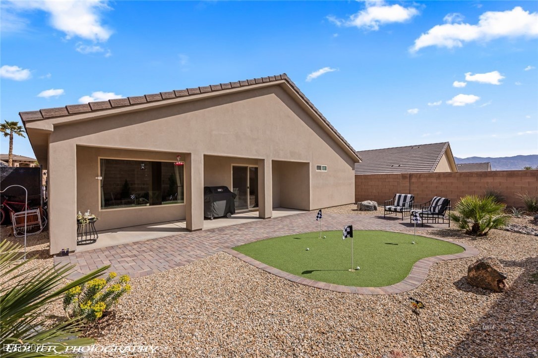 942 Shadow Hawk Ridge Mesquite, NV 89027 - Photo 56 of 67 Rear view of property featuring a putting area, a patio area, stucco siding, and fence