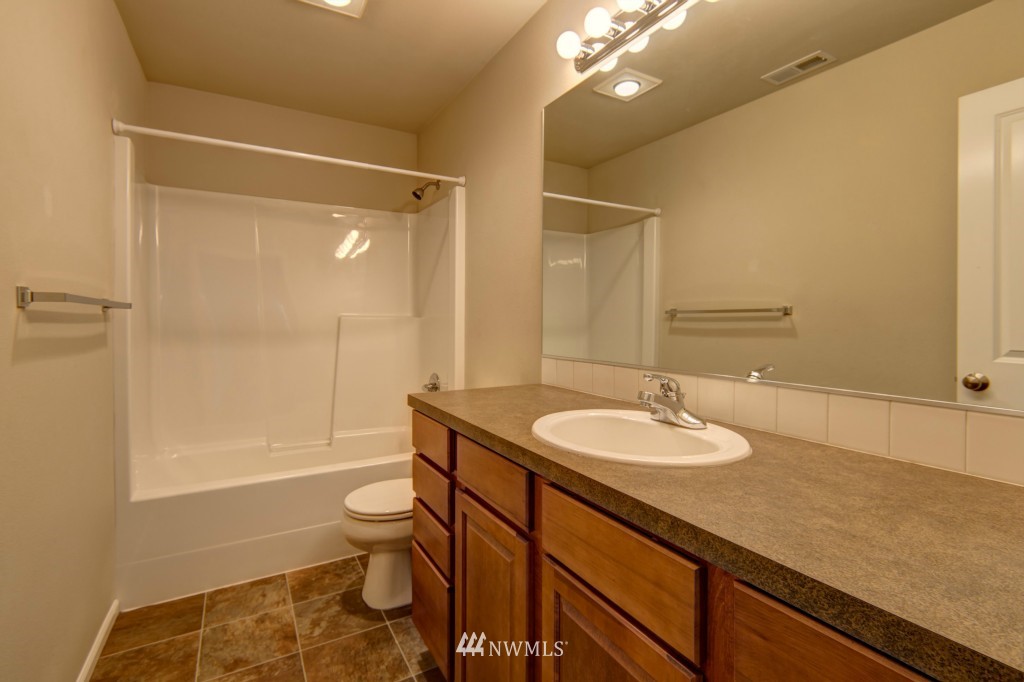 16123 35th Drive Southeast Bothell, WA 98012 - Photo 10 of 13 a bathroom with a granite countertop sink a toilet a mirror and shower