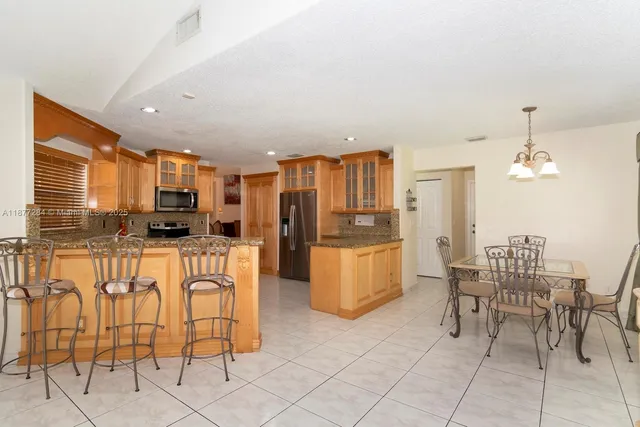 a kitchen with stainless steel appliances kitchen island granite countertop a refrigerator and cabinets