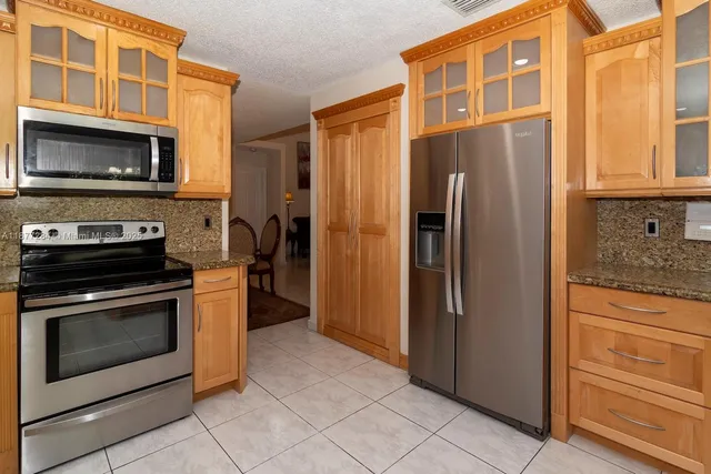 a kitchen with stainless steel appliances granite countertop a refrigerator and a stove top oven