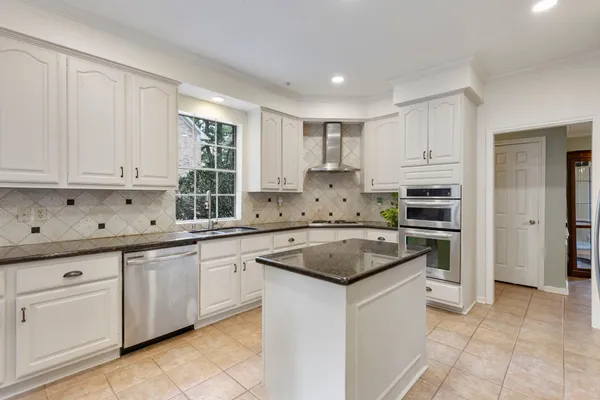 a kitchen with stainless steel appliances granite countertop a sink a stove a dining table and chairs