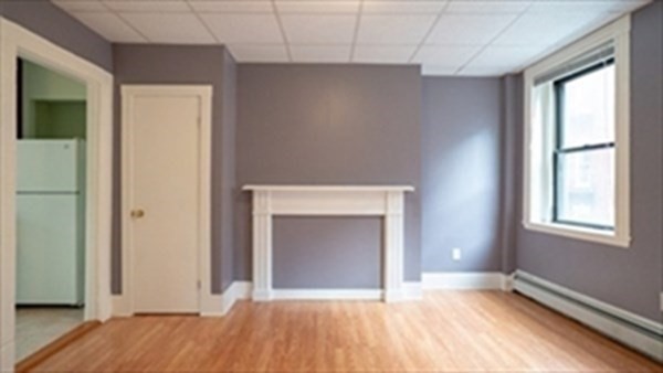 a view of an empty room with window and fire place