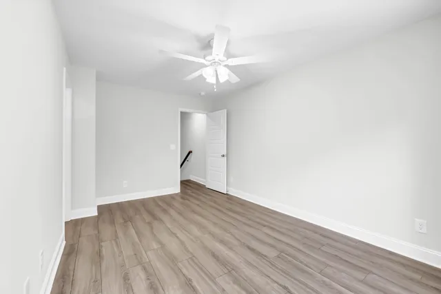 an empty room with wooden floor and fan