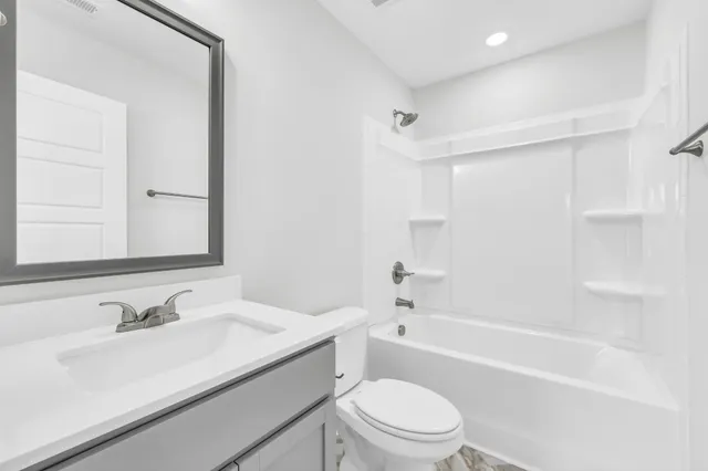 a bathroom with a granite countertop sink a toilet and shower