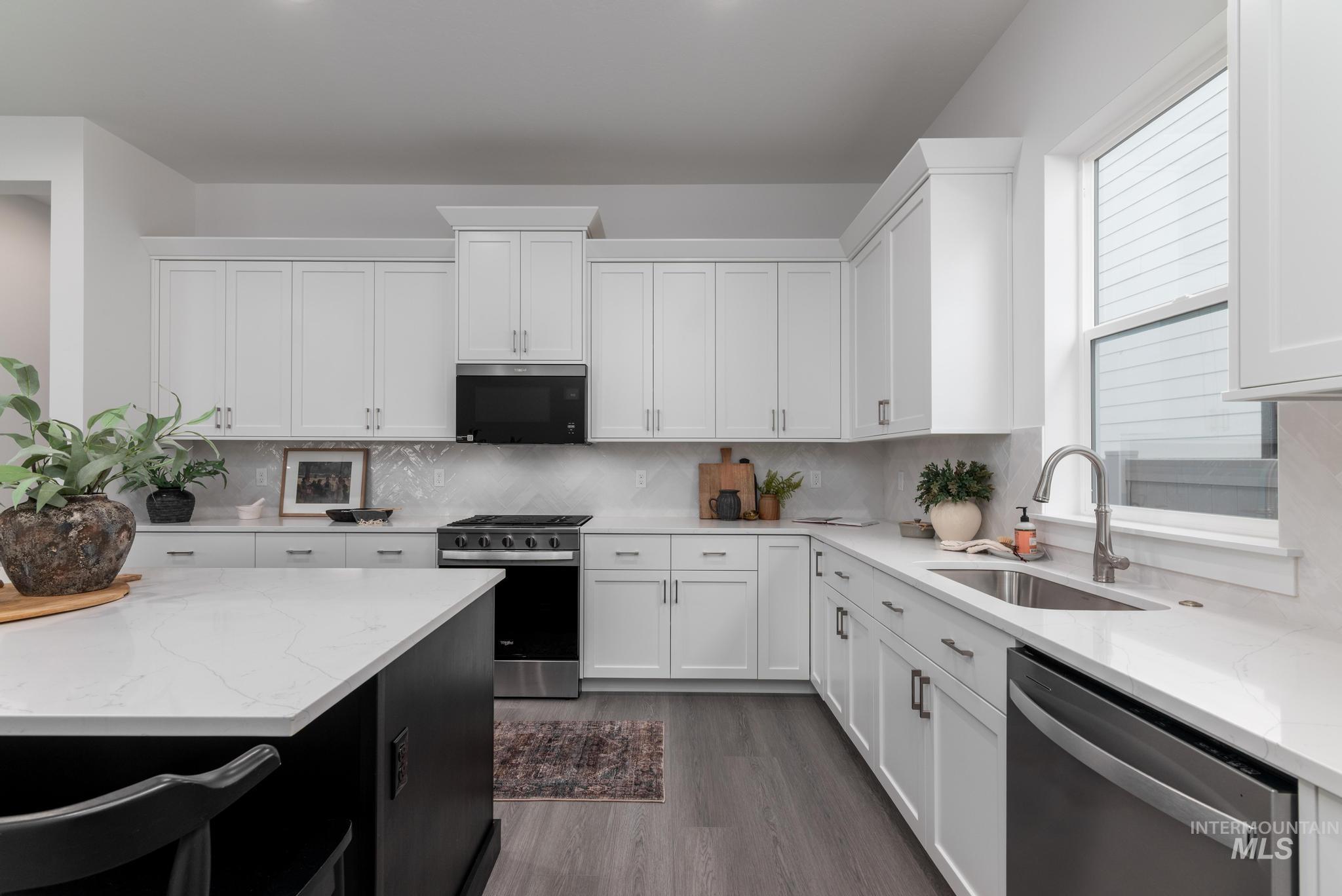 8629 West Stillmore Street Star, ID 83669 - Photo 11 of 27 Kitchen with light stone counters, white cabinets, appliances with stainless steel finishes, dark cabinets, and dark wood-style flooring