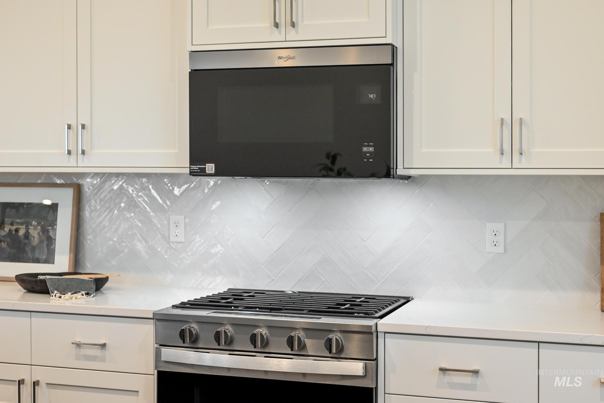 8629 West Stillmore Street Star, ID 83669 - Photo 13 of 27 Kitchen with white cabinetry, stainless steel appliances, tasteful backsplash, and light stone counters