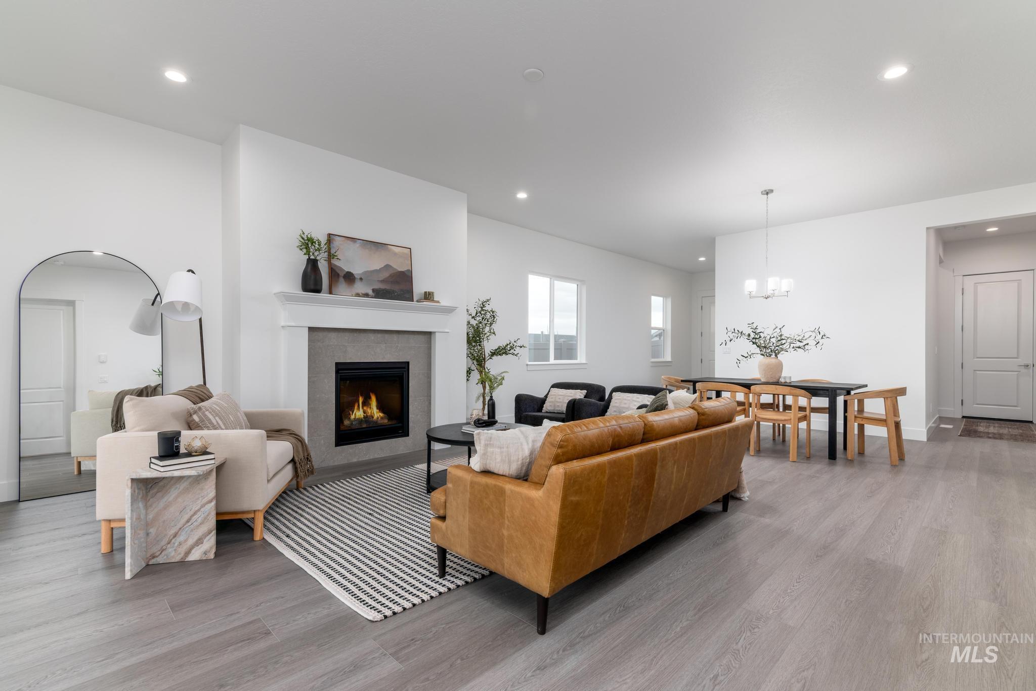 8629 West Stillmore Street Star, ID 83669 - Photo 5 of 27 Living room with a tiled fireplace, light wood-style floors, recessed lighting, and a chandelier