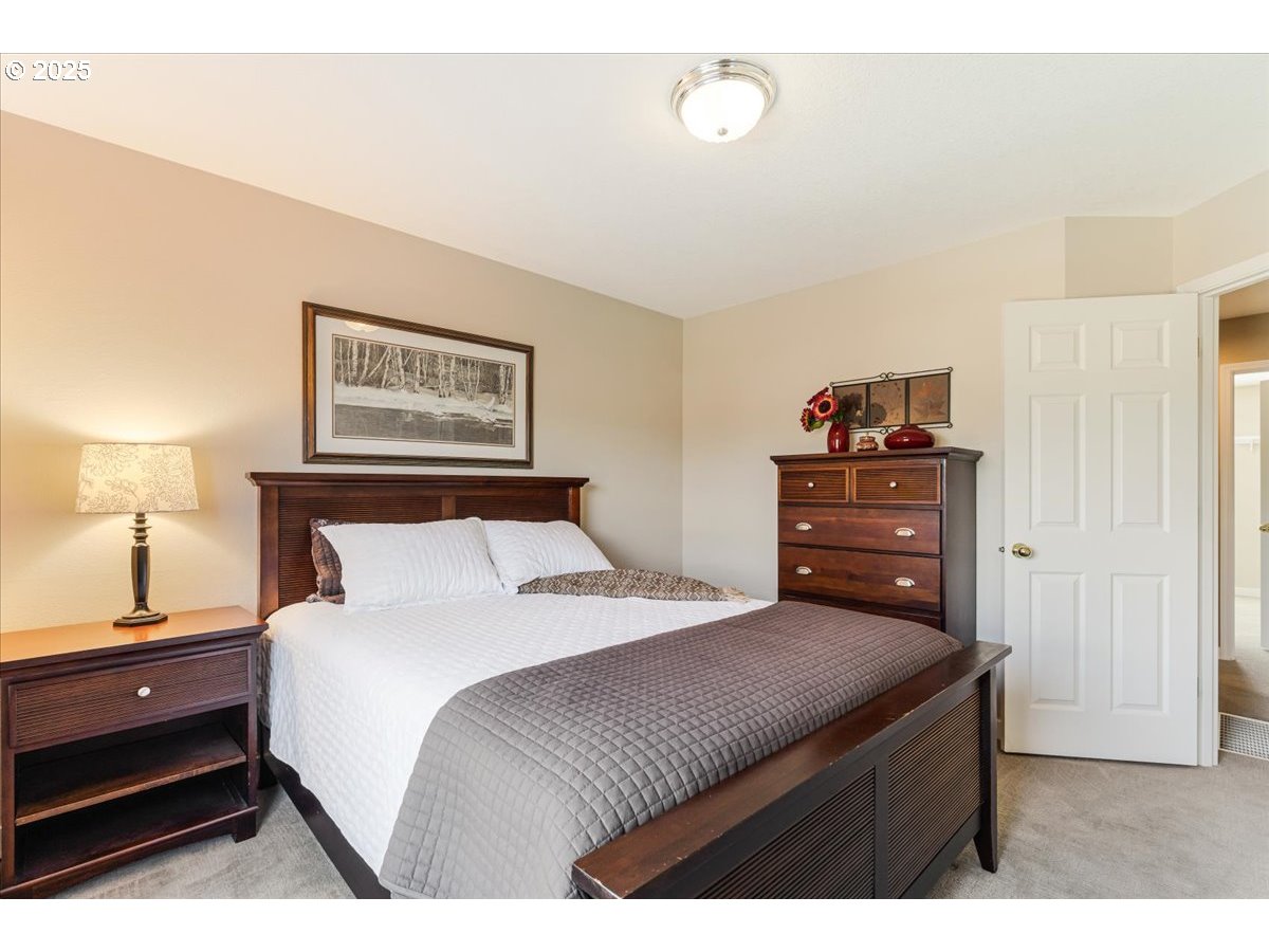 16706 Northwest Waterford Way Portland, OR 97229 - Photo 33 of 45 a bedroom with a bed and a lamp on dresser