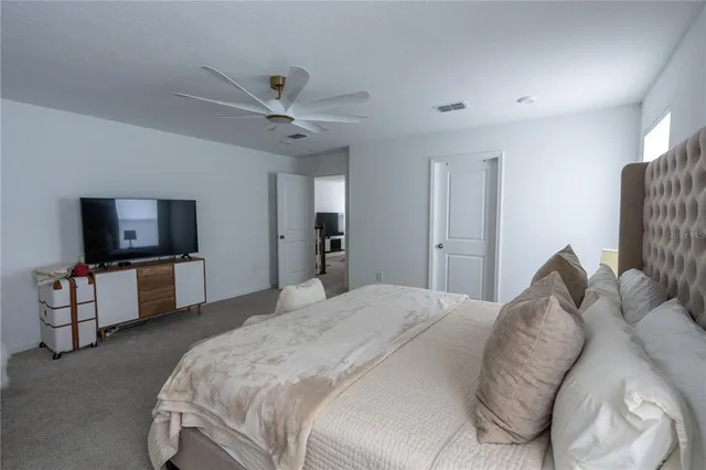 a spacious bedroom with a bed and a flat screen tv
