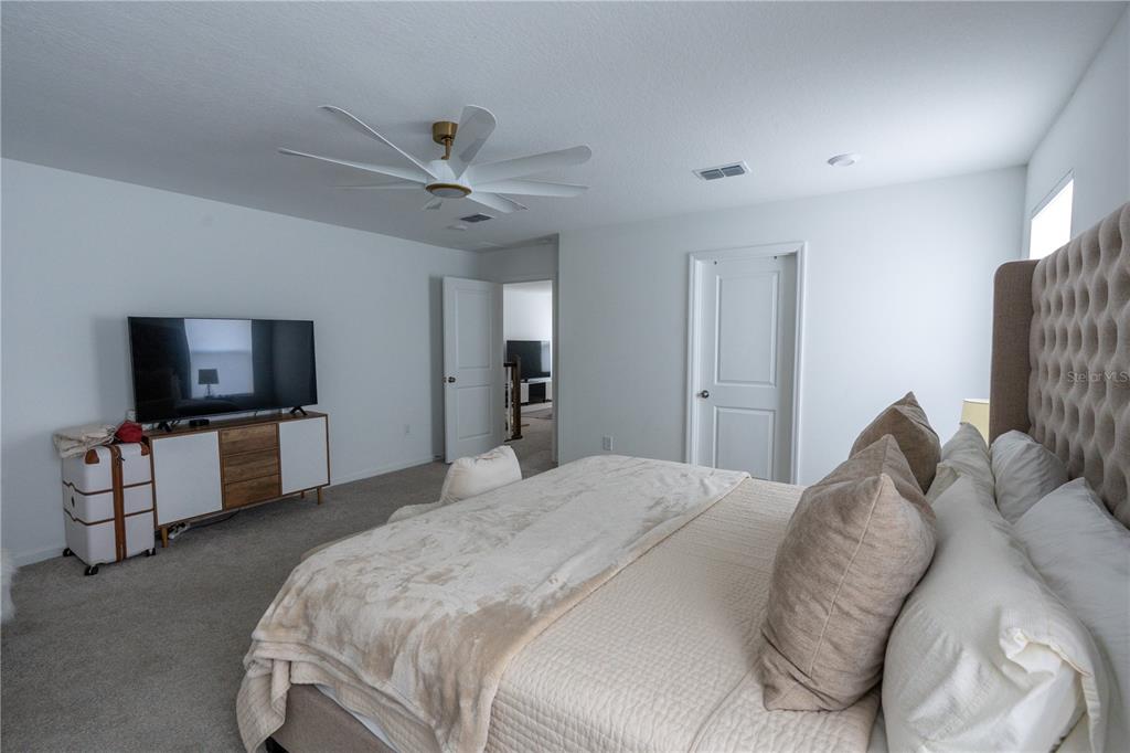 2069 Valencia Blossom Street Clermont, FL 34711 - Photo 15 of 24 a spacious bedroom with a bed and a flat screen tv
