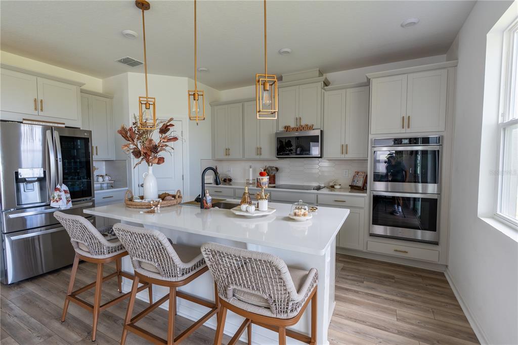 2069 Valencia Blossom Street Clermont, FL 34711 - Photo 3 of 24 a kitchen with stainless steel appliances a dining table chairs stove and refrigerator