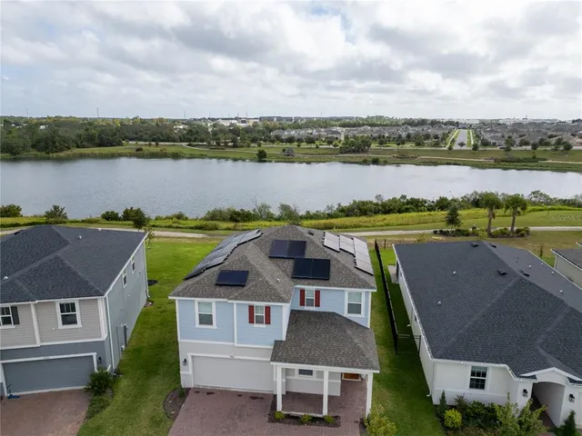 an aerial view of a house with outdoor space and lake view in back