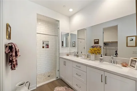 a spacious bathroom with double vanity a mirror and shower