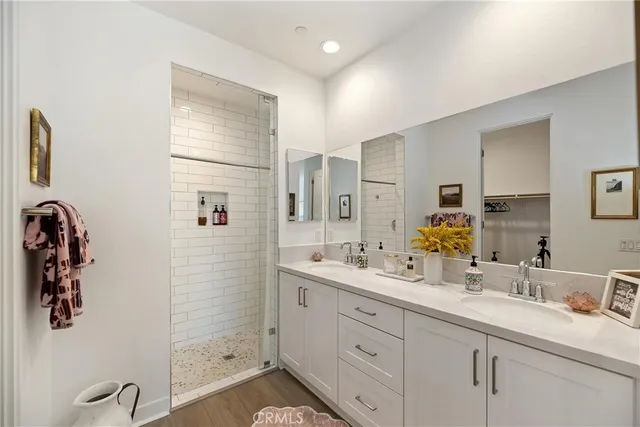 a spacious bathroom with double vanity a mirror and shower