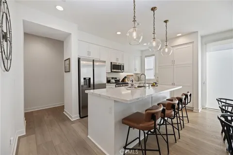 a kitchen with kitchen island a dining table chairs stainless steel appliances and cabinets