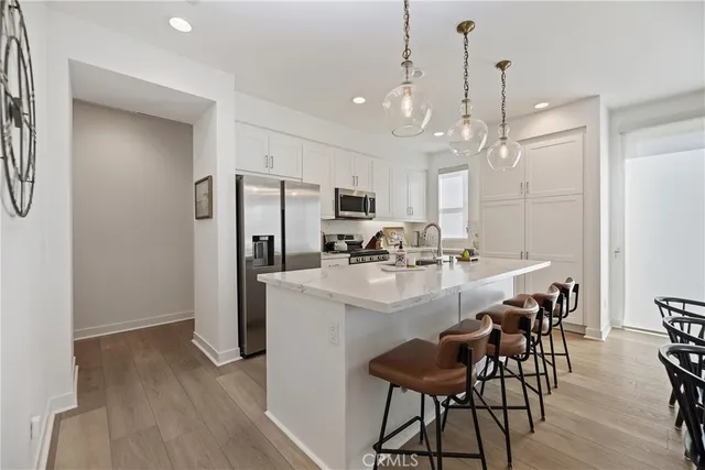 a kitchen with kitchen island a dining table chairs stainless steel appliances and cabinets