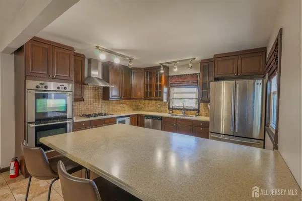 a kitchen with stainless steel appliances a refrigerator a sink a stove a dining table and chairs
