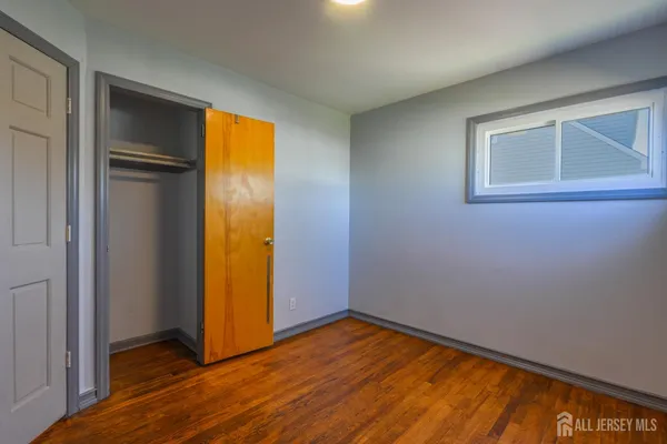 a view of empty room with wooden floor and closet