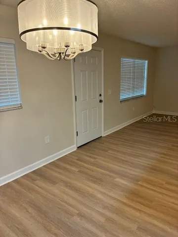 an empty room with a chandelier fan and wooden floor