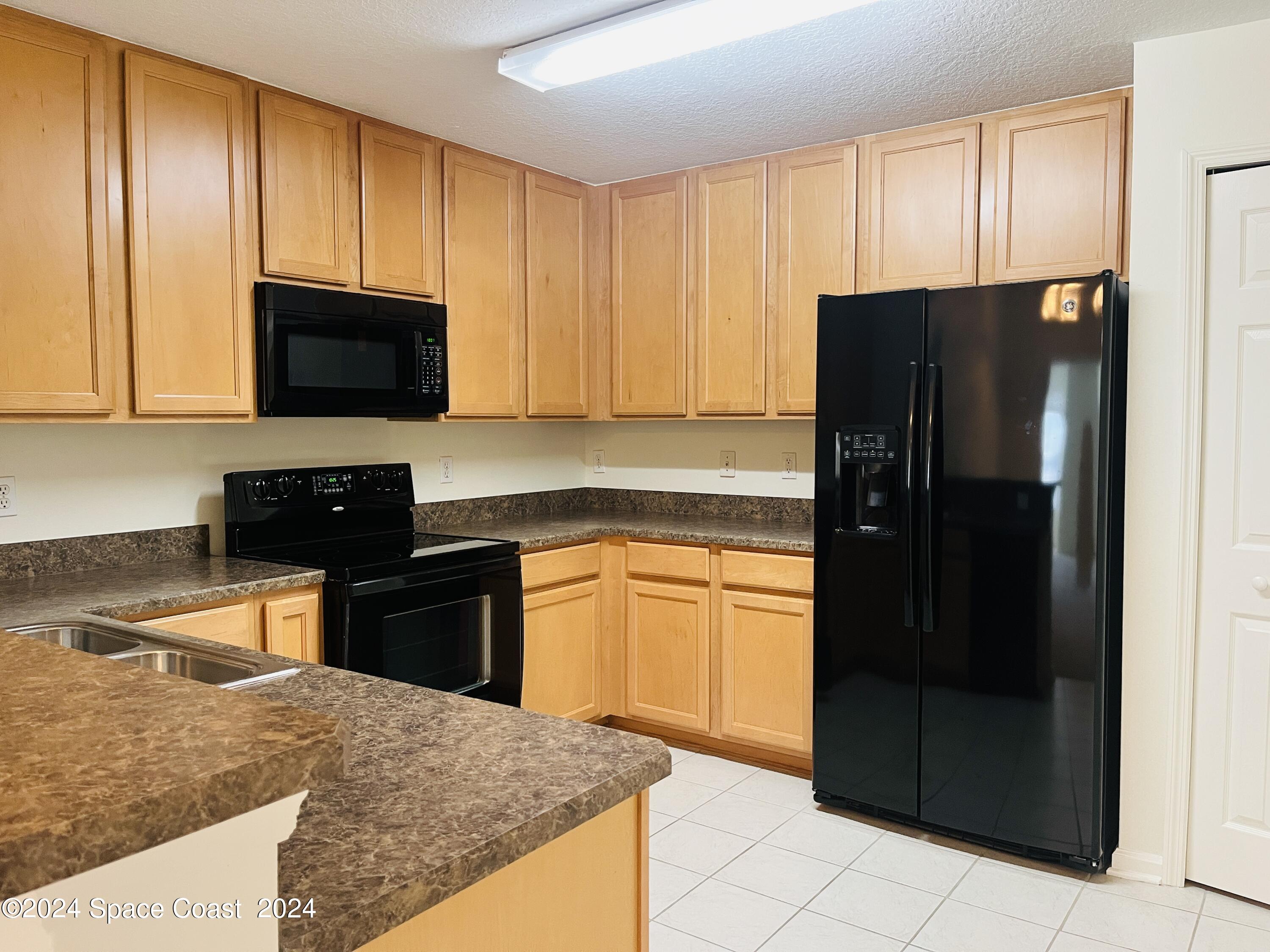 4006 Meander Place, Unit 201 Rockledge, FL 32955 - Photo 3 of 20 a kitchen with granite countertop wooden cabinets and refrigerator