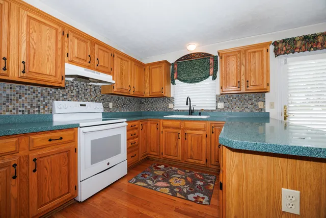 a kitchen with stainless steel appliances granite countertop a stove a sink dishwasher and cabinets with wooden floor