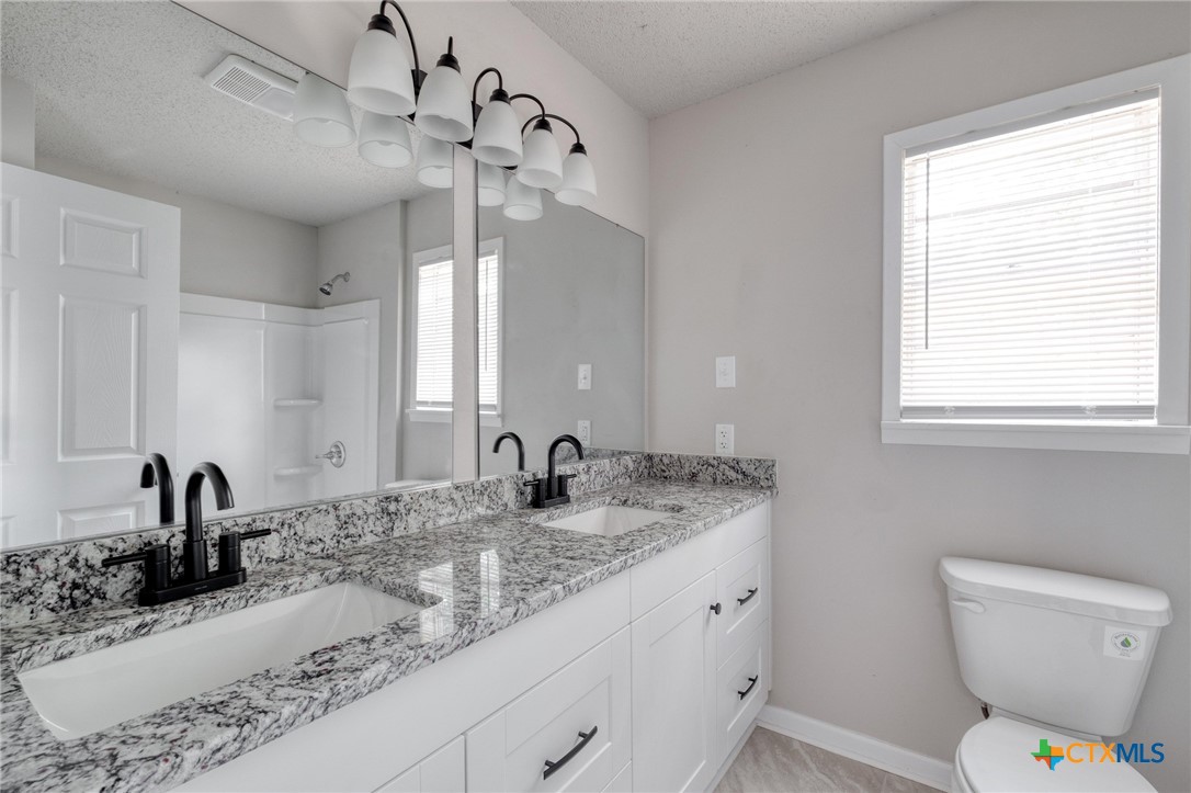 4978 Sparta Road Belton, TX 76513 - Photo 21 of 32 a bathroom with a granite countertop sink a toilet and mirror