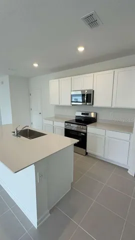 a kitchen with a sink a stove top oven and cabinets