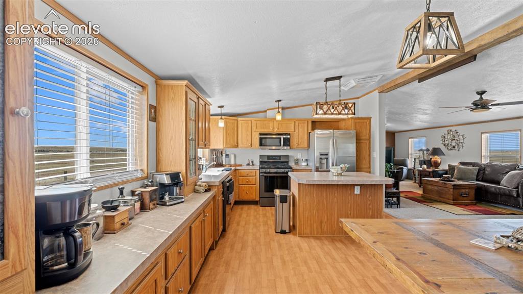 33975 Highway 94 Yoder, CO 80864 - Photo 13 of 40 Open-concept kitchen featuring wood-finish cabinetry, stainless steel appliances, a center island, and wood-finish flooring throughout