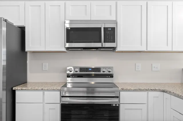 a kitchen with granite countertop white cabinets and stainless steel appliances