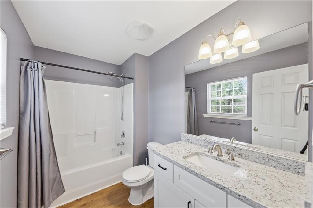 1318 Reece Road Woodstock, GA 30188 - Photo 25 of 40 a bathroom with a granite countertop sink toilet a large mirror a bathtub and shower