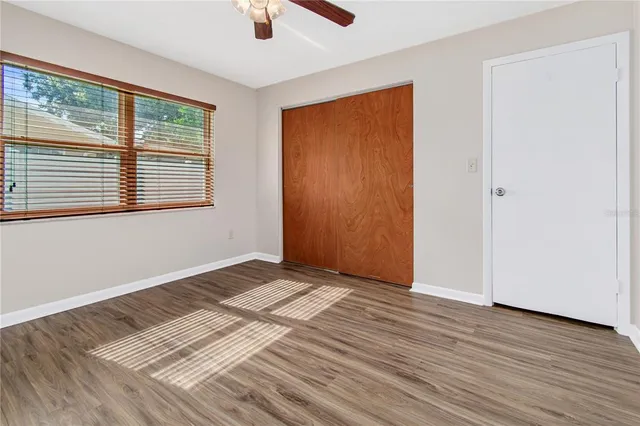 a view of an empty room with wooden floor and a window