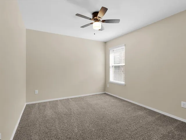 an empty room with a ceiling fan and window
