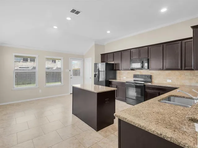 a kitchen with stainless steel appliances granite countertop a stove top oven a sink a refrigerator and white cabinets