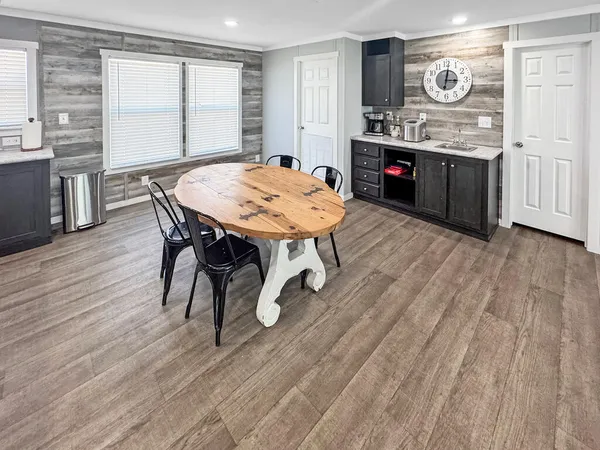 a open kitchen with stainless steel appliances granite countertop a dishwasher a stove a dining table and chairs with wooden floor