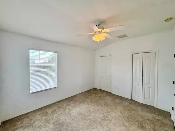 an empty room with a window and ceiling fan