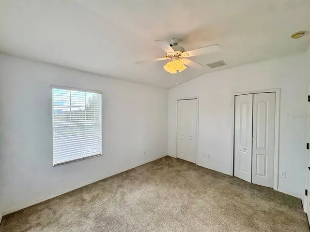 an empty room with a window and ceiling fan