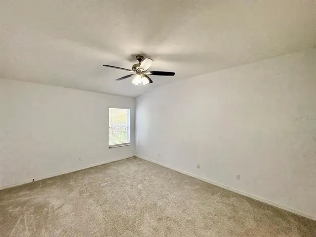 an empty room with a chandelier fan and windows
