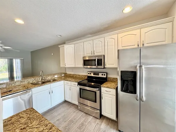 a kitchen with stainless steel appliances granite countertop a stove a sink and a refrigerator