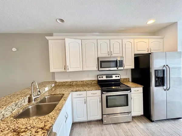 a kitchen with granite countertop white cabinets and stainless steel appliances
