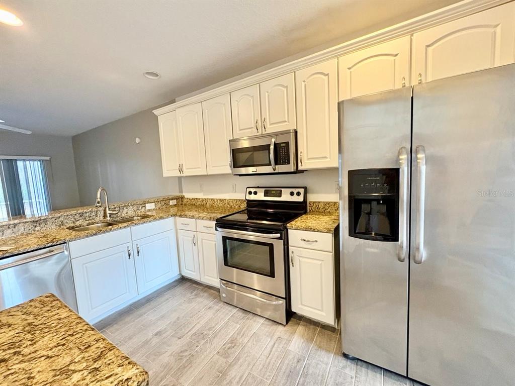 15619 Stable Run Drive Spring Hill, FL 34610 - Photo 9 of 28 a kitchen with granite countertop a refrigerator stove and microwave