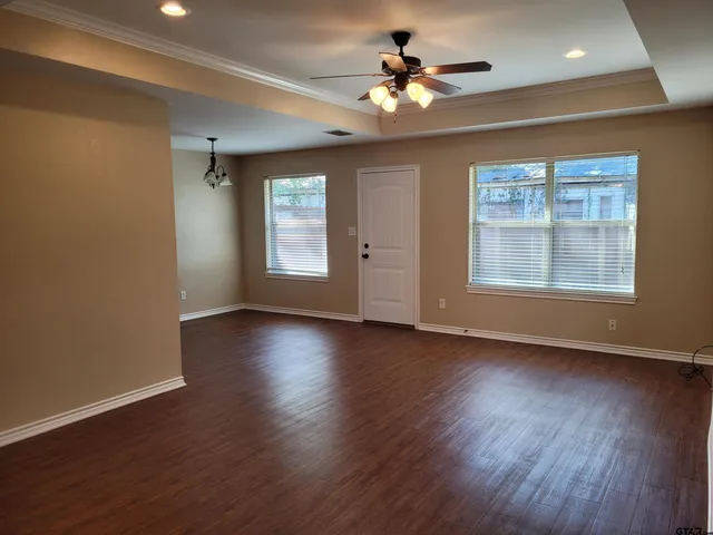 a view of an empty room with a window and wooden floor