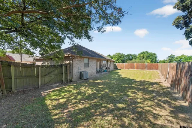 a view of a house with a small yard plants and a large tree