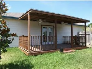 a backyard of a house with wooden fence and large trees