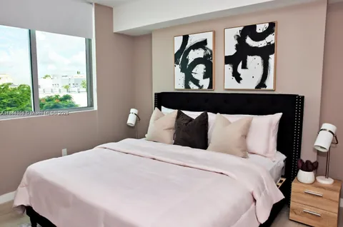 a large white bed in a bedroom next to a window